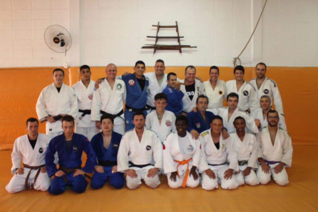 Equipe de judô em pose parafoto debaixo de um simbolo japonês